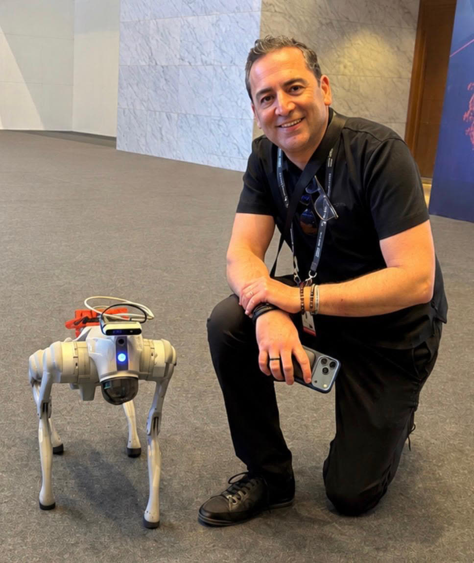 Mike Beatty kneeling beside a robot dog